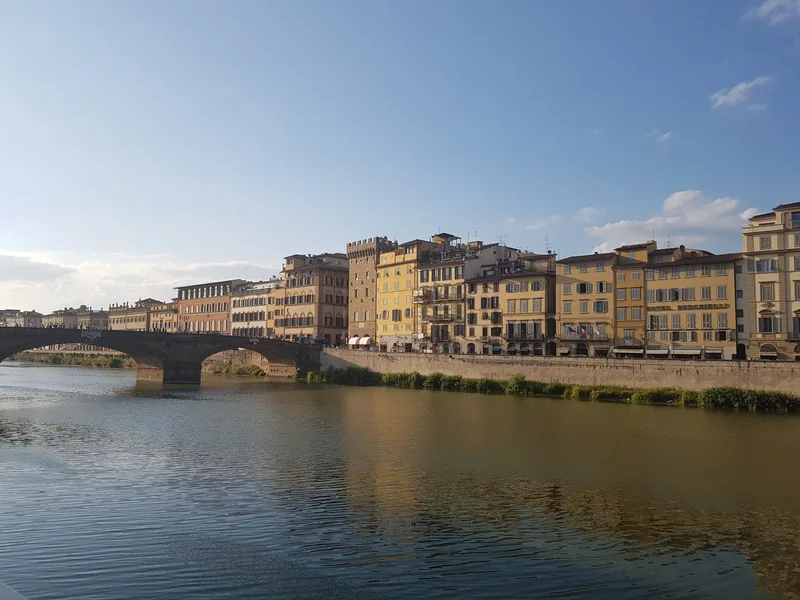 Lungarno Firenze al tramonto: palazzi storici color ocra riflessi nell'Arno — itinerario 2-3 giorni a Firenze