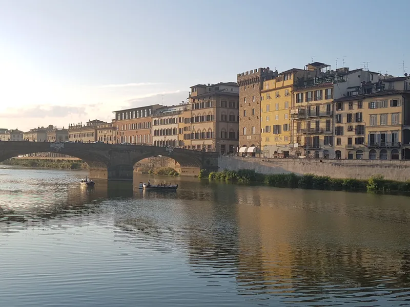 Barche sull'Arno al tramonto nell'Oltrarno di Firenze con i palazzi storici del Lungarno sullo sfondo