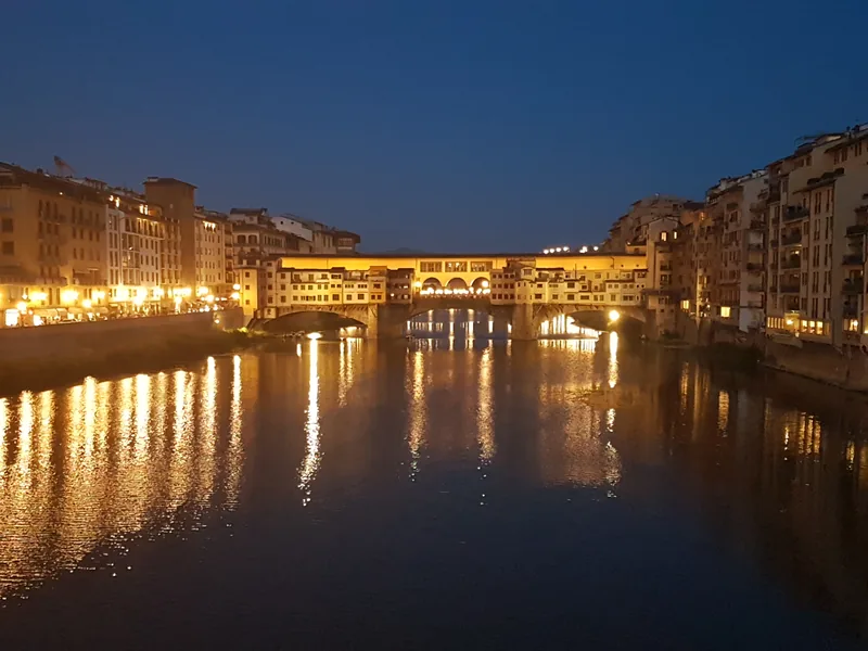 Ponte Vecchio Firenze di notte: luci dorate riflesse sull'Arno — tra i monumenti più fotografati d'Italia