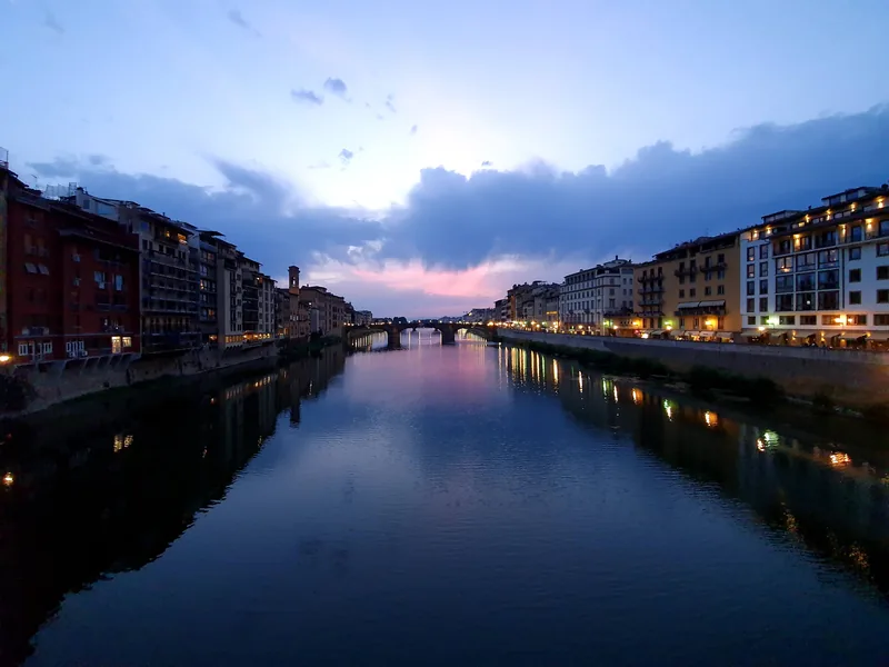 Galleria degli Uffizi Firenze di notte: loggiato illuminato con riflessi nell'Arno — apertura serale il giovedì fino alle 22